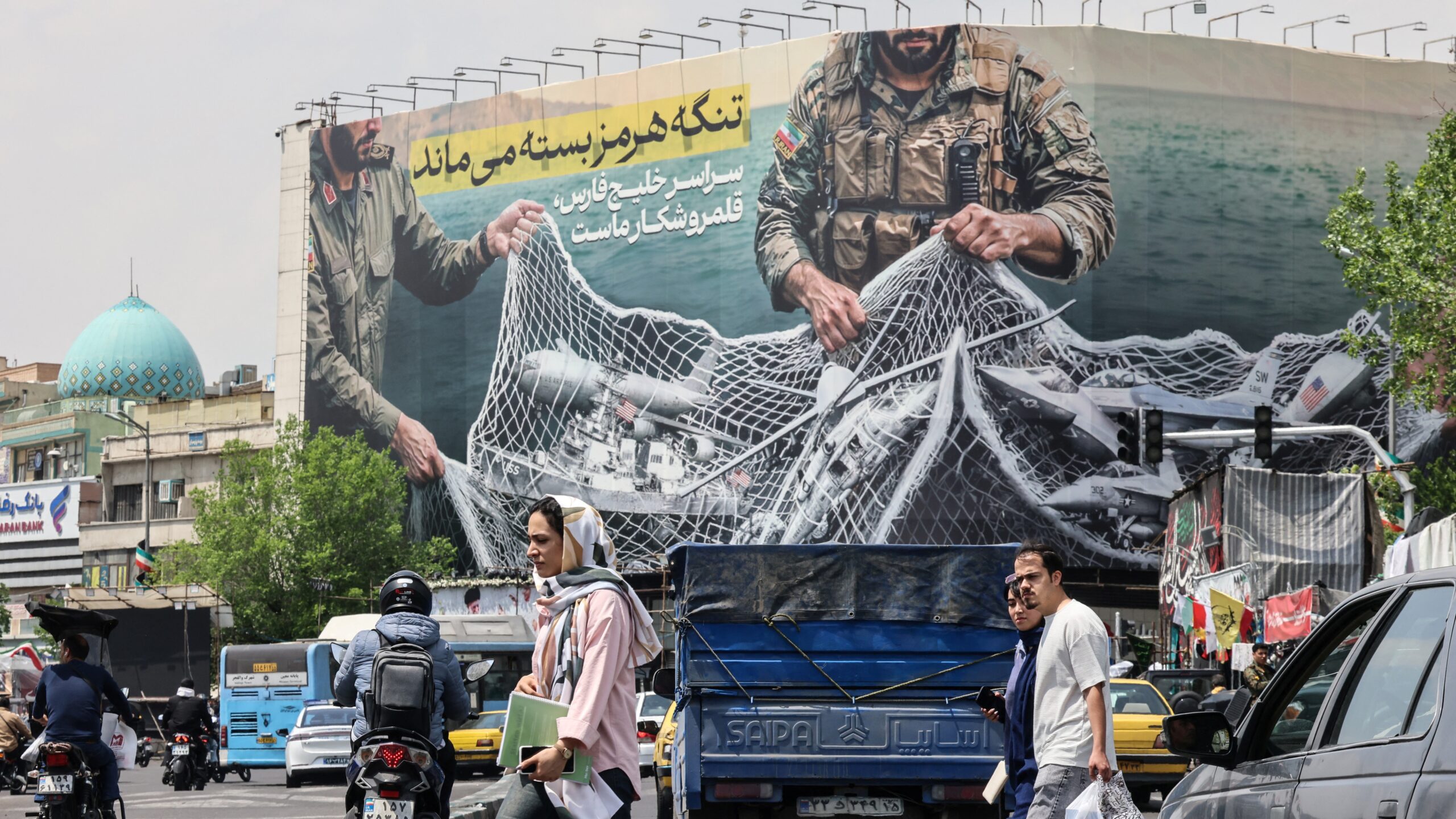 Iranian walks past a giant billboard reading 'The Strait of Hormuz remains closed' at the Revolution Square in Tehran on April 22, 2026, amid a ceasefire in the region.