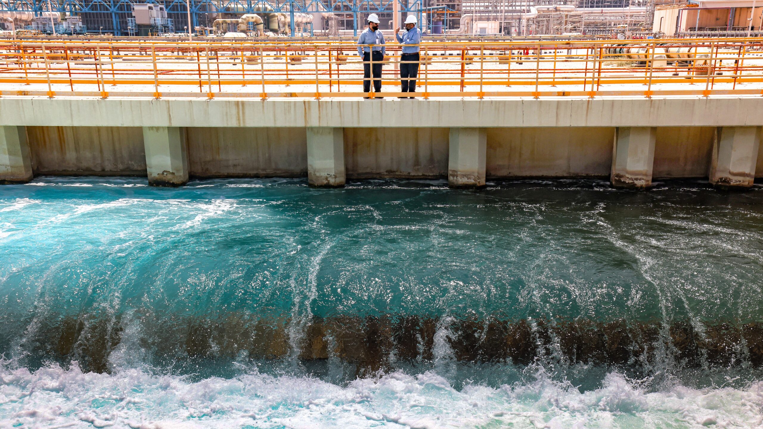 In this picture taken on March 30, 2023, Mohamed Ali al-Qahtani (L), Phase General Manager at the Ras al-Khair water desalination plant, owned by the Saudi government's Saline Water Conversion Corporation, speaks with an employee at the facility in Ras al-Khair along the Gulf coast in eastern Saudi Arabia. (Photo by Fayez Nureldine / AFP)