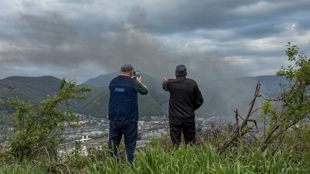 Local residents observe smoke rising above buildings following a recent drone attack on the Tuapse oil refinery in Tuapse, Krasnodar region on April 29, 2026,