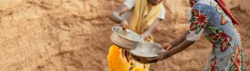 Two children collecting water in a rural area using jerry cans