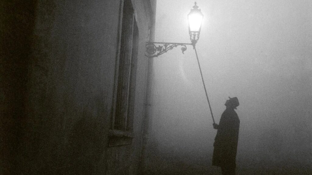 A lamplighter lights a street gas lamp on a foggy winter evening in Budapest, 1960