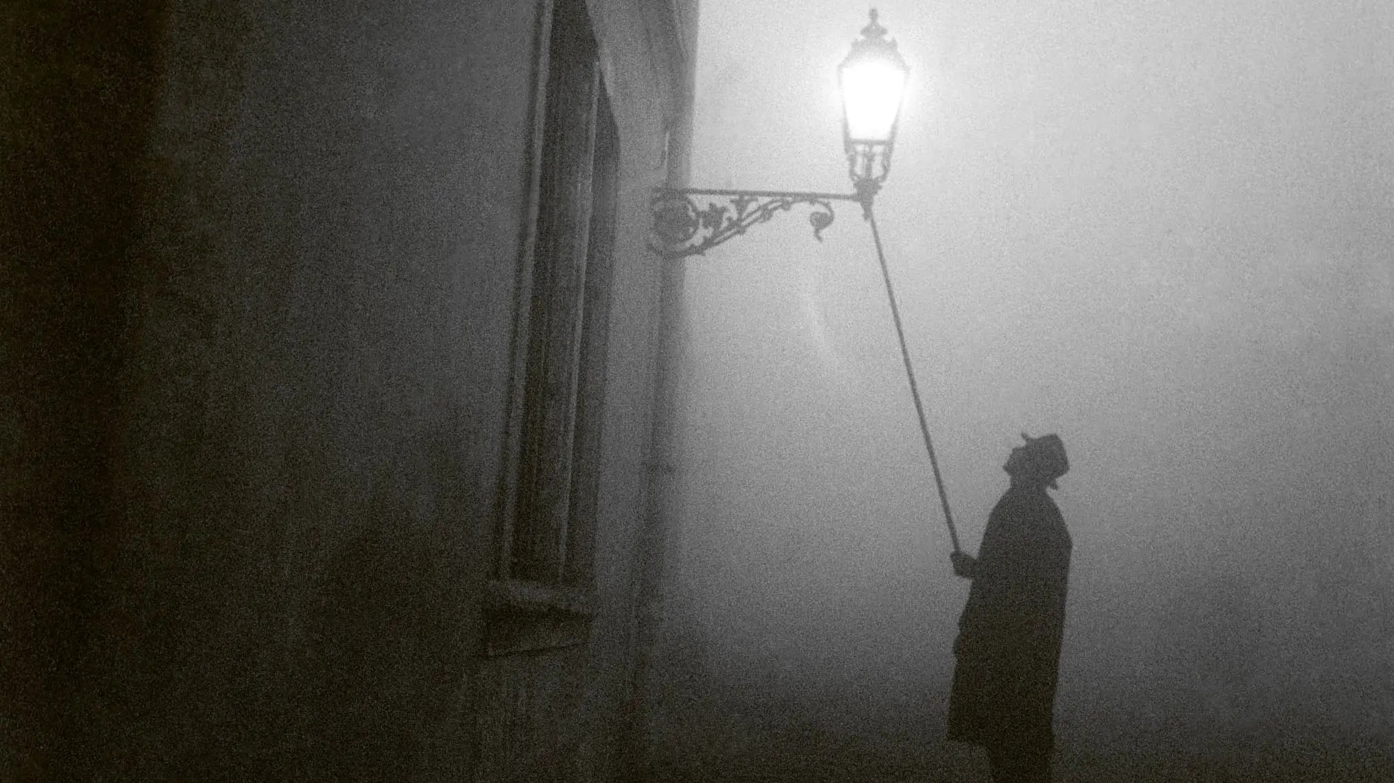 A lamplighter lights a street gas lamp on a foggy winter evening in Budapest, 1960